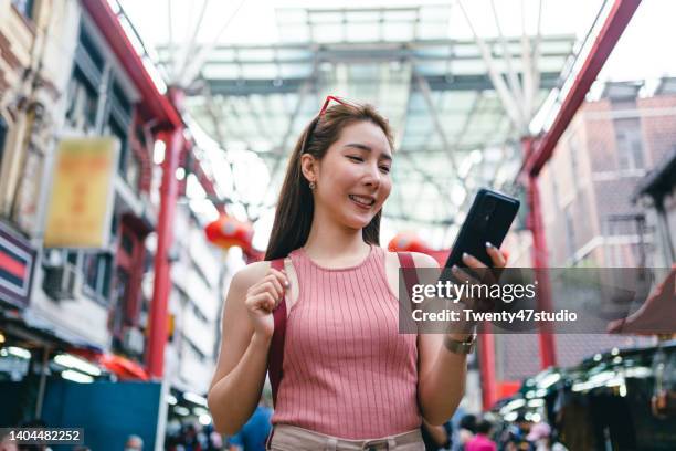 young asian woman using a smartphone while traveling in petaling street - malaysia city stock pictures, royalty-free photos & images