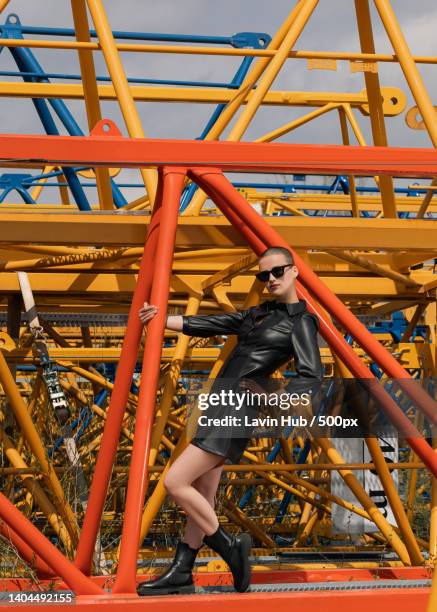 portrait of futuristic young woman wearing sunglasses posing at construction site - editorial photography stock pictures, royalty-free photos & images