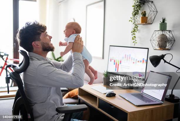 multitasking-vater, der sich um den kleinen sohn kümmert, während er im homeoffice arbeitet. - lebensstil stock-fotos und bilder