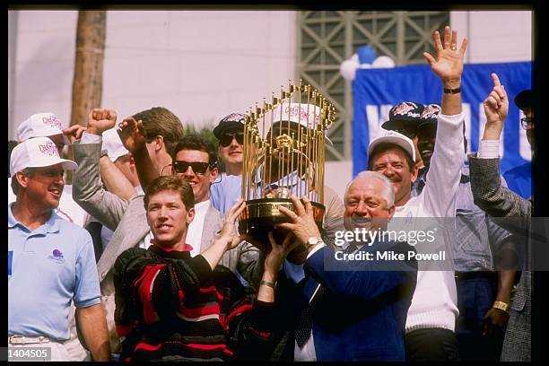 Pitcher and World Series MVP Orel Hershiser and manager Tommy Lasorda of the Los Angeles Dodgers hold up the World Series trophy in front of a crowd...