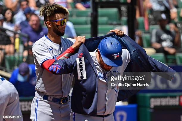 Alejandro Kirk of the Toronto Blue Jays is assisted by Lourdes Gurriel Jr. #13 of the Toronto Blue Jays with putting on the home run jacket after his...
