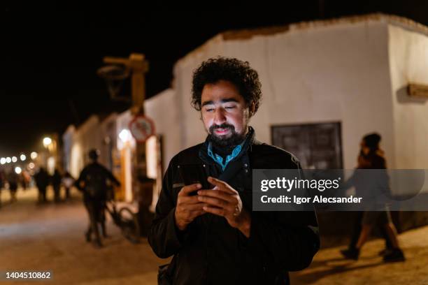 mann mit smartphone in san pedro de atacama - san pedro de atacama stock-fotos und bilder
