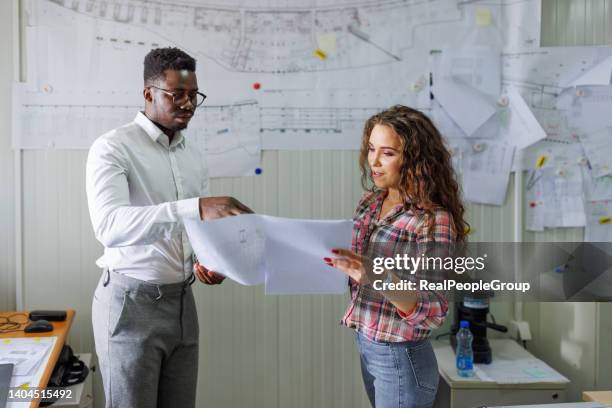 mann und frau schauen sich die blaupausen im büro an und machen ein neues projekt. - construction worker office people stock-fotos und bilder