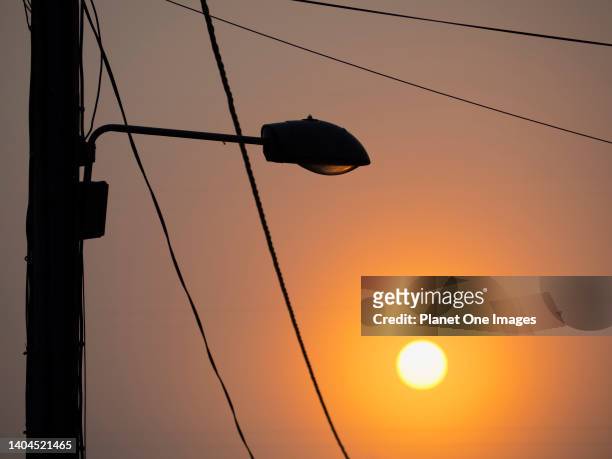 Street light and cables in Lower Radley Village, Oxfordshire, illuminated by the rising sun c1.