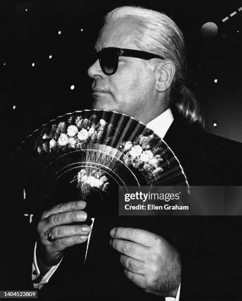 Portrait of German fashion designer Karl Lagerfeld as he holds a folding fan, Paris, France 1995.