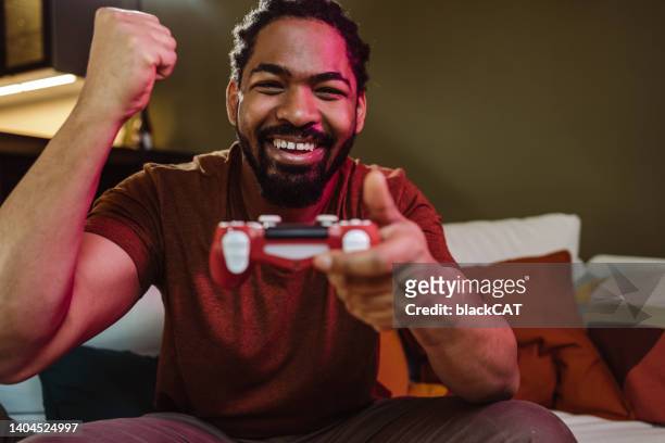 porträt eines aufgeregten und fröhlichen mannes, der ein videospiel spielt - gaming controller stock-fotos und bilder