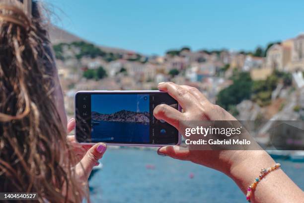 woman taking a photo of the views in symi - symi ストックフォトと画像