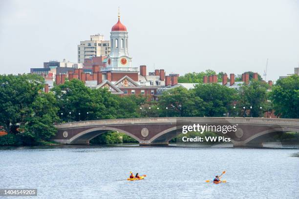 Kayaking in John W. Weeks Bridge and clock tower over Charles River in Harvard University campus in Cambridge, Boston Massachusetts..