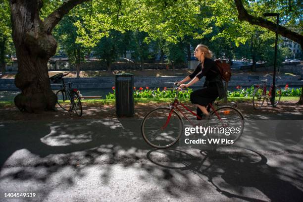 Woman on a bicycle on a promenade on the banks of the River Aura in Turku Finland..