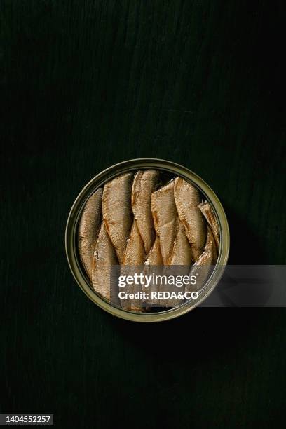 Open can with canned baltic smoked sprats in oil over black wooden background. Top view, copy space.