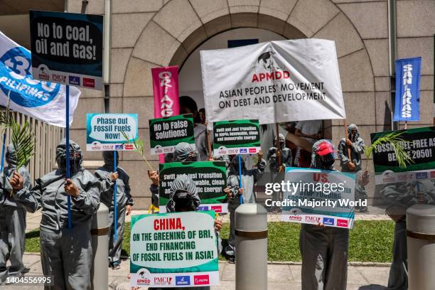 Climate activists dressed in costumes carry signs as they protest outside the Asian Development Bank headquarters in Mandaluyong City. The group...