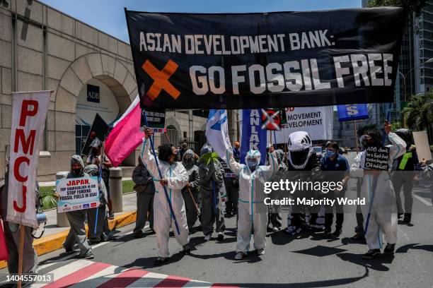 Climate activists dressed in costumes carry signs as they protest outside the Asian Development Bank headquarters in Mandaluyong City. The group...