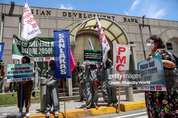 Climate activists dressed in costumes carry signs as they protest outside the Asian Development Bank headquarters in Mandaluyong City. The group...