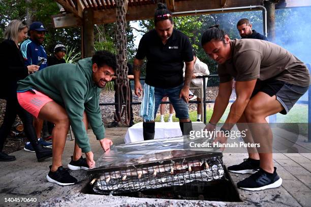 Ardie Savea and Caleb Clarke help lay food in a hangi during their visit to the Waitangi Treaty grounds on June 23, 2022 in Waitangi, New Zealand.
