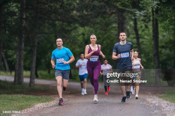 eine aufnahme einer gruppe von marathonläufern, die durch die natur laufen - kilometer stock-fotos und bilder