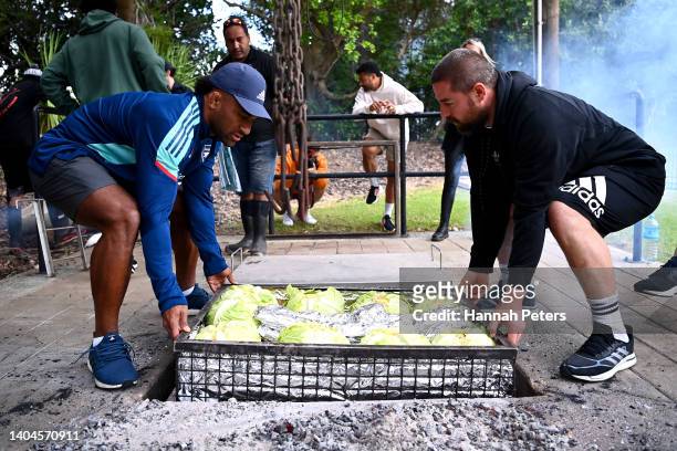 Sevu Reece and Dane Coles help lay food in a hangi during their visit to the Waitangi Treaty grounds on June 23, 2022 in Waitangi, New Zealand.