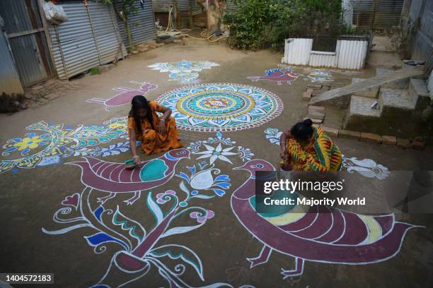 Woman and girls paint Alpona, on the ground on the eve of the Hindu festival Makar Sankranti. Makar Sankranti or Uttarayan or Maghi or simply...