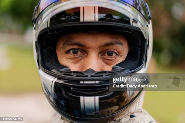 close up portrait of malaysian man wearing helmet getting ready for motorcycle ride - crash helmet stock pictures, royalty-free photos & images