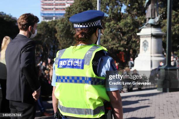 Female police officer watches as people gather for a ceremony held by representatives of Parliament and Te Atiawa Taranaki Whanui to mark the full...