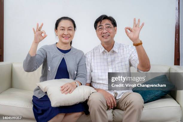 old couple show ok sign hands in the living room at home - ok sign stock pictures, royalty-free photos & images