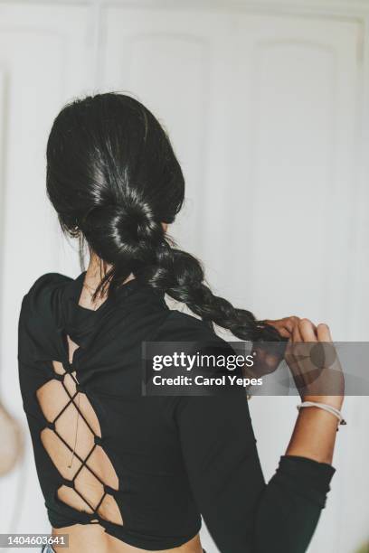 rear view young latina doing baraided hair at home - braids stock pictures, royalty-free photos & images