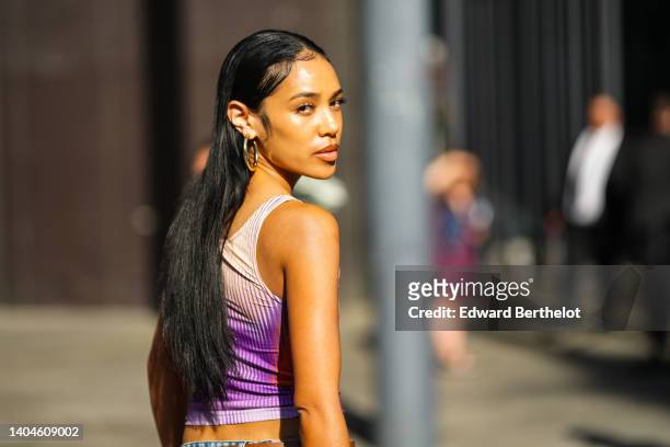 Aleali May wears gold large earrings, a white / red / purple ribbed body print pattern cropped tank-top, outside the Rhude show, during Paris Fashion...