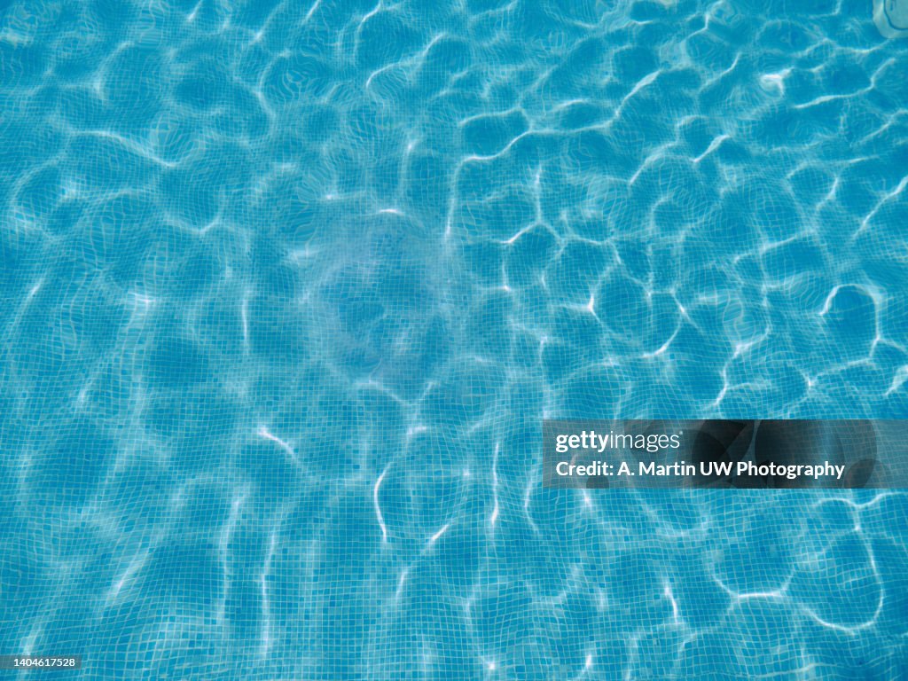 Abstract view of bottom caustics of swimming pool with ripple...