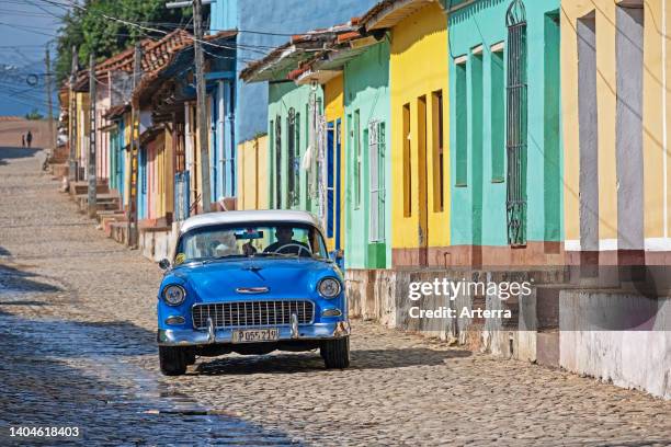 Blue vintage American Chevrolet car in colonial cobbled street with pastel coloured houses in the city Trinidad, Sancti Spíritus Province, Cuba.