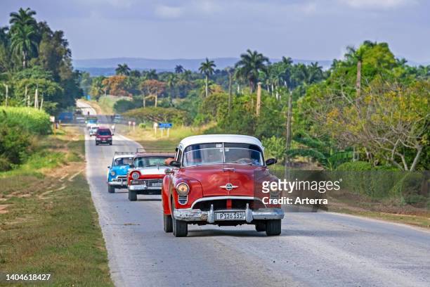 Classic American cars driving along the Carretera Central/CC/Central Road, west-east highway in the Sancti Spíritus Province on the island Cuba.