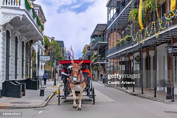 Horse-drawn carriage with tourists and hotels in Royal street, French Quarter/Vieux Carré in the city New Orleans, Louisiana, United States/USA.