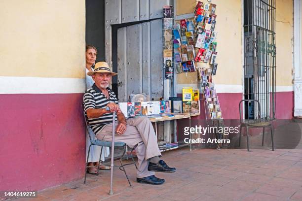 Proud Cuban senior bookseller posing in front of his little bookshop/bookstore in the city Sancti Spíritus on the island Cuba, Caribbean.