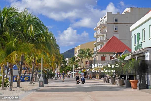Tourists walking on boulevard with palm trees along the beach in capital city Philipsburg of the Dutch island part of Sint Maarten in the Caribbean.