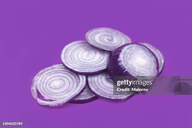 cut-up red onion on purple background. - cutting red onion stock pictures, royalty-free photos & images