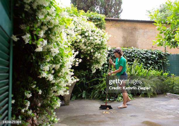 woman sweeping backyard - woman sweeping stock pictures, royalty-free photos & images