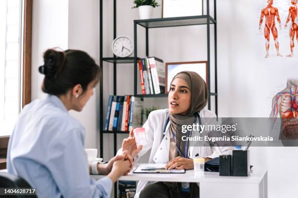 close up of a young woman having an asian doctor's appointment. - arab doctor patient stock-fotos und bilder