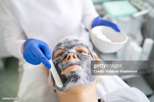 applying a facial mask to a woman's face in the beauty salon - hyperpigmentation stockfoto's en -beelden
