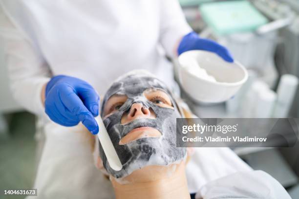 applying a facial mask to a woman's face in the beauty salon - hyperpigmentation stock pictures, royalty-free photos & images