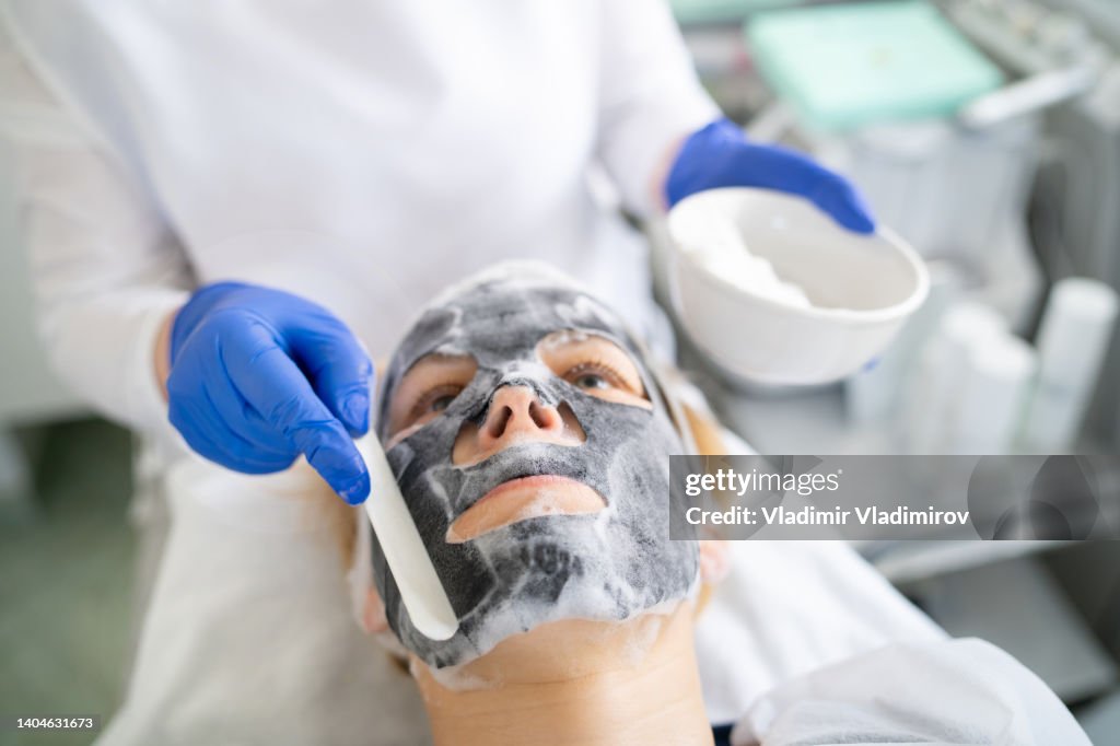 Applying a facial mask to a woman's face in the beauty salon