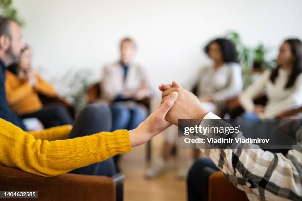 un primer plano de pacientes tomados de la mano durante una reunión de apoyo - malos hábitos fotografías e imágenes de stock