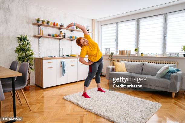young overweight woman stretching before exercising - yoga rug stock pictures, royalty-free photos & images