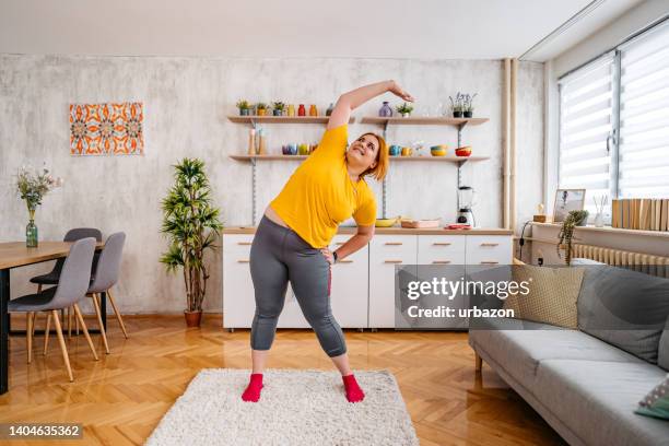 young overweight woman stretching before exercising - yoga rug stock pictures, royalty-free photos & images