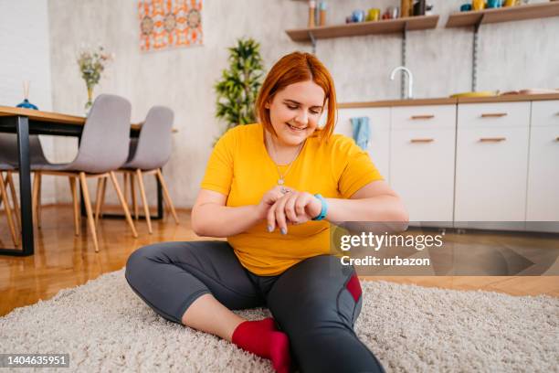 mujer joven comprobando su actividad física en un reloj inteligente - checking sports fotografías e imágenes de stock