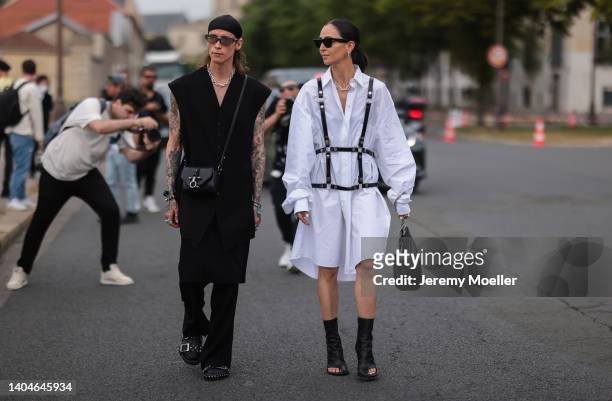 Simon Nygard seen wearing a black scarf as hairband, a black sunglasses, silver necklace, a black sleeveless long buttoned gilet/vest, a black wide...