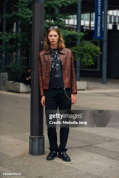 Model Cosme Voisin wears a brown python leather jacket, black ACDC Highway to Hell band t-shirt, blue jeans, a pocket chain, and black leather...