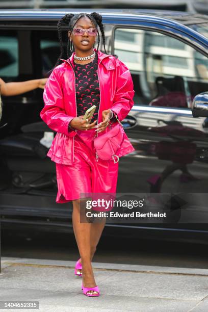 Guest wears pink sunglasses, silver earrings, a silver and diamonds large necklace, a black with neon pink mood print pattern long sleeves t-shirt...