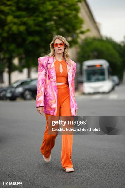 Guest wears a pink / white / orange tie and dye print pattern oversized blazer jacket, a brown shiny leather crocodile print pattern shoulder bag,...
