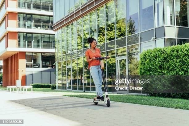 african american young woman riding electric scooter in the city - step well stockfoto's en -beelden