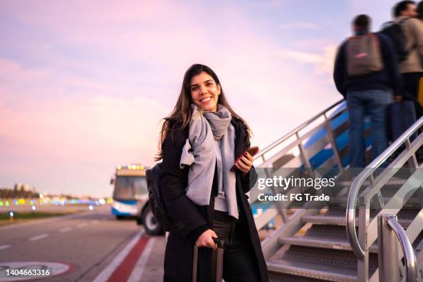 portrait of woman traveling entering in airplane - boarding stockfoto's en -beelden