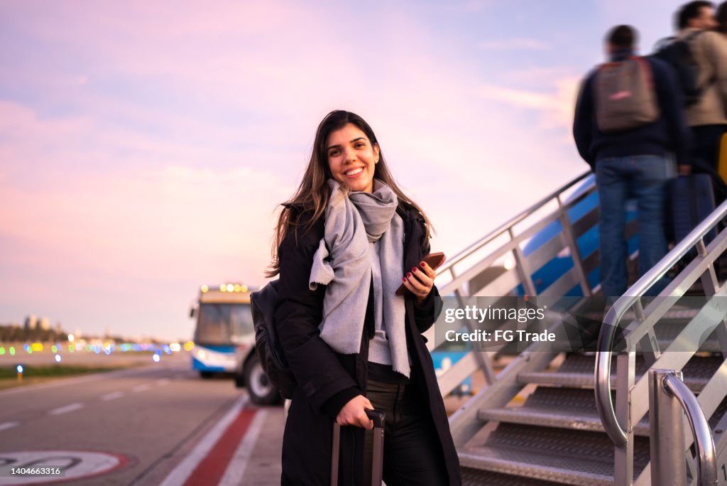 Portrait of woman traveling entering in airplane