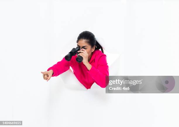 generation z young women in front of white background wearing sweatshirt and holding binoculars - looking around on white background stock pictures, royalty-free photos & images